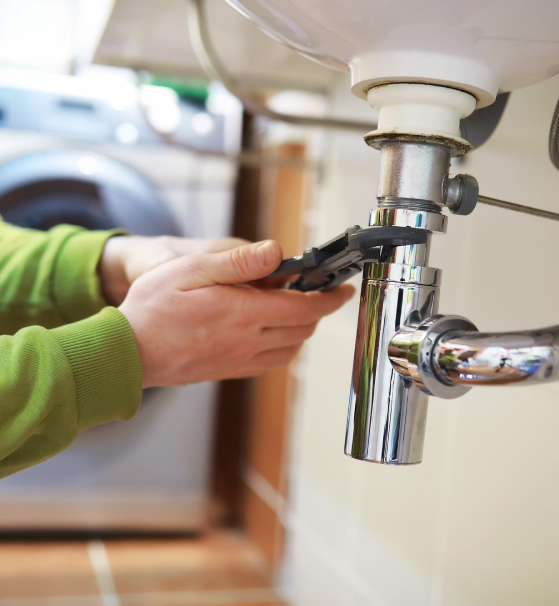 using a wrench on a pipe under sink