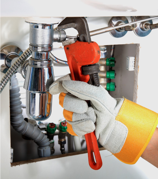 a wrench being used on a pipe under a sink