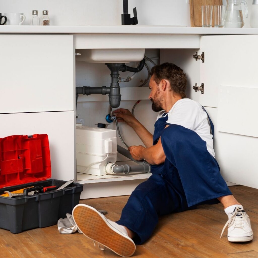 Plumber inspecting pipes under a sink