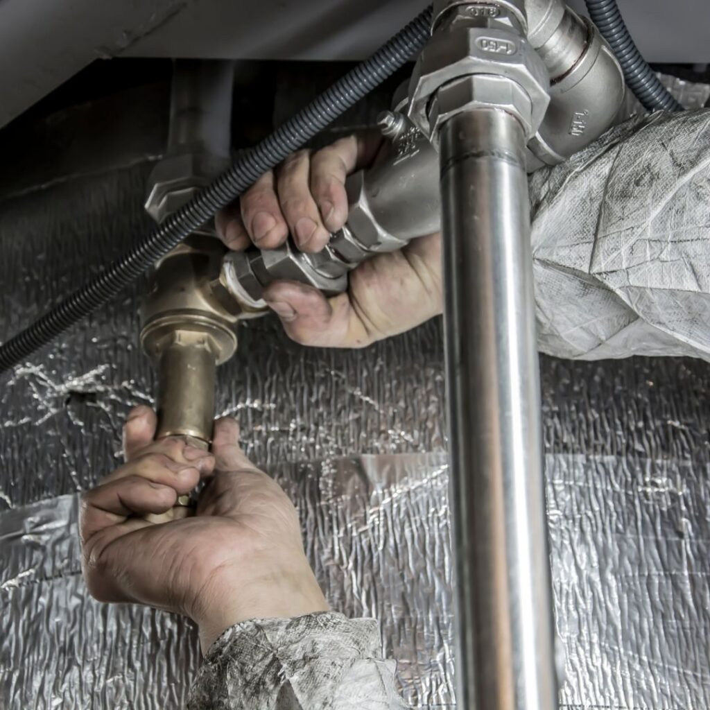 plumber working on pipes under sink