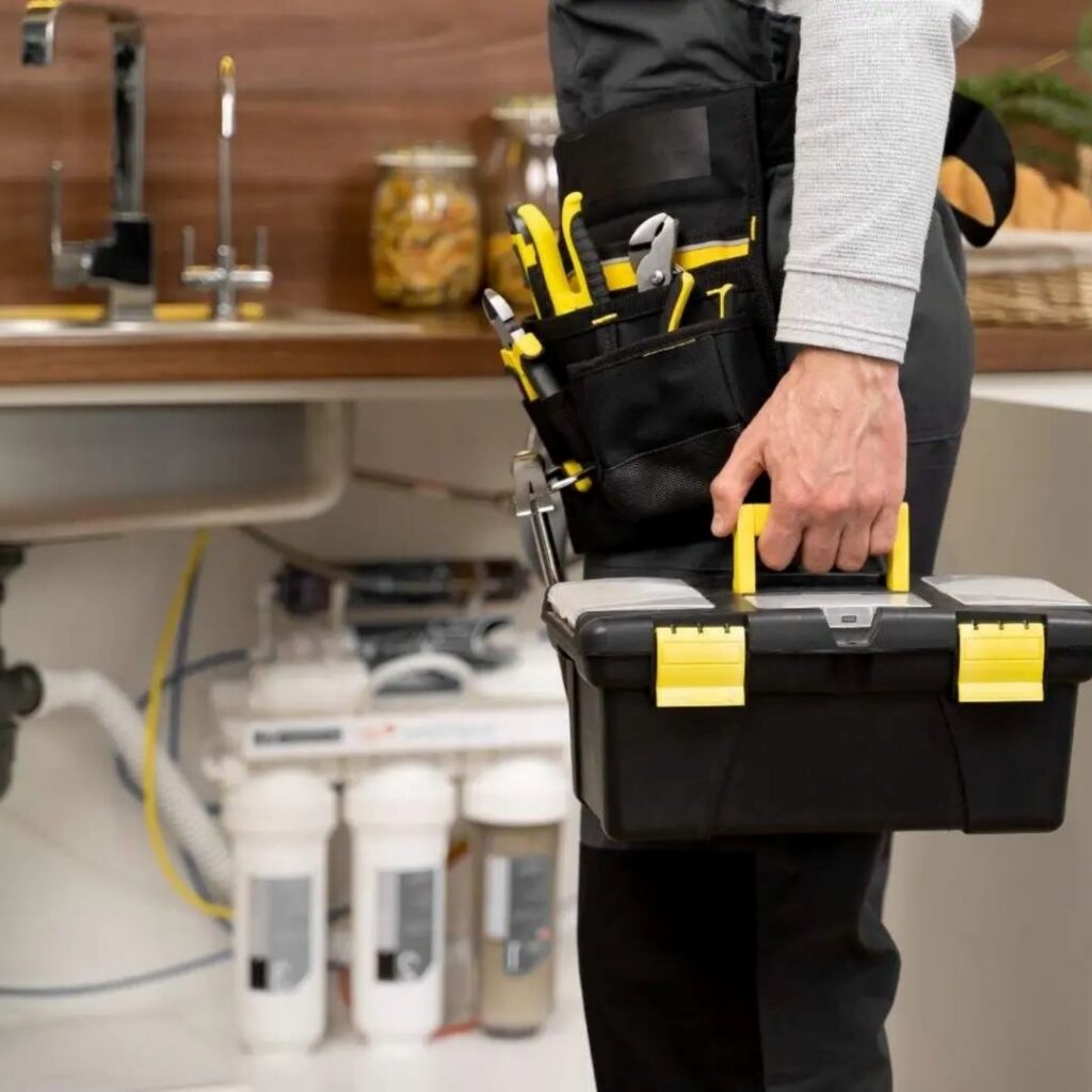 plumber holding tool box next to sink